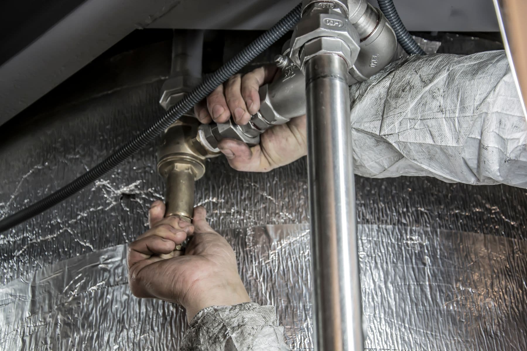 Hands tightening metal pipe fittings