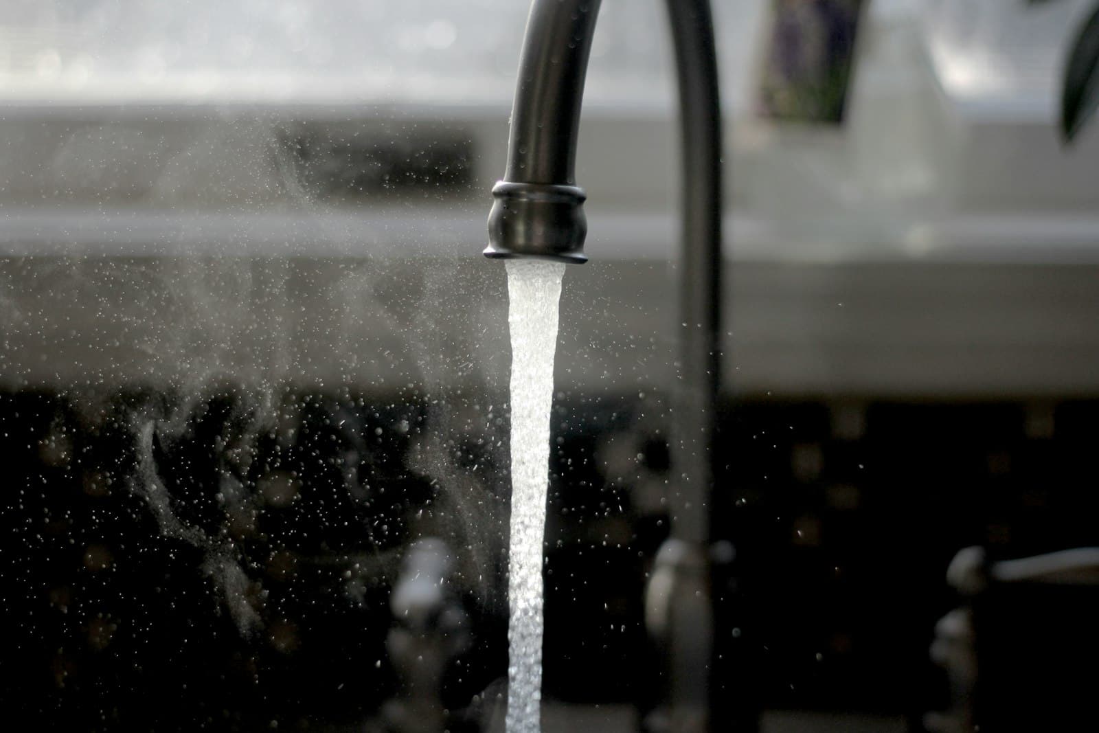 Black kitchen faucet with water running into a sink